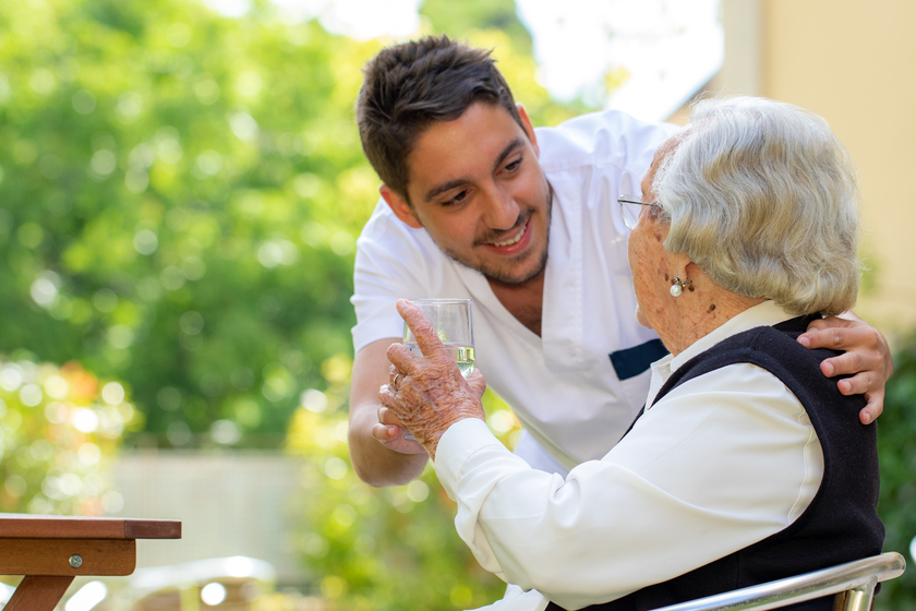 Male nurse showing affection to old woman in garden. Male nurse showing affection to old woman in garden.
