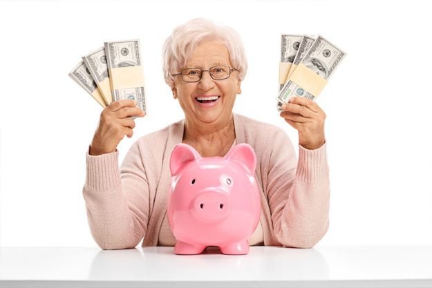 Cheerful elderly woman with a piggybank and money bundles Cheerful elderly woman with a piggybank and money bundles
