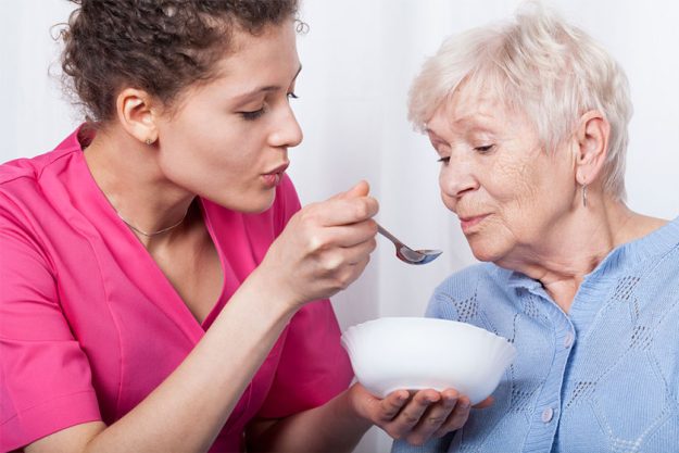 Nurse feeding an older lady Nurse feeding an older lady
