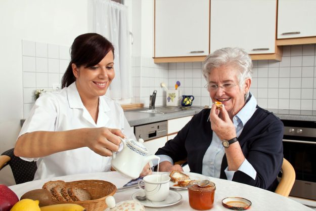 Nurse helps elderly woman at breakfast Nurse helps elderly woman at breakfast