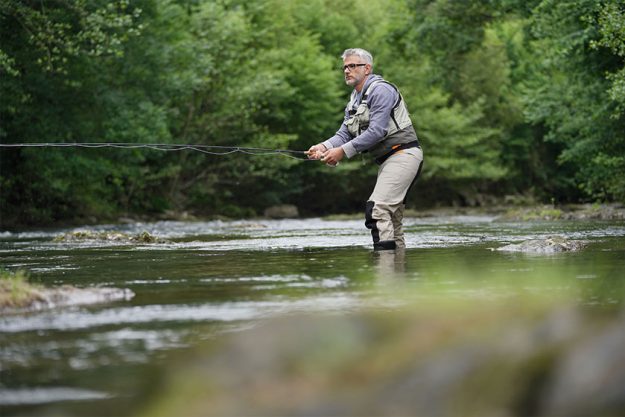 Fisherman fly-fishing in river Fisherman fly-fishing in river