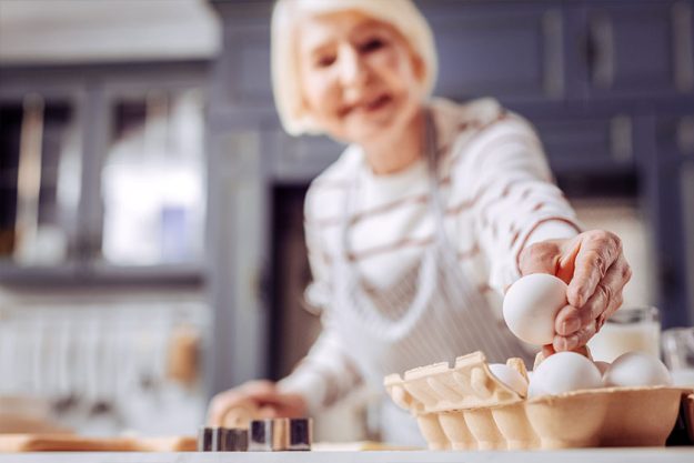 Close up of senior woman taking one egg from the box Close up of senior woman taking one egg from the box