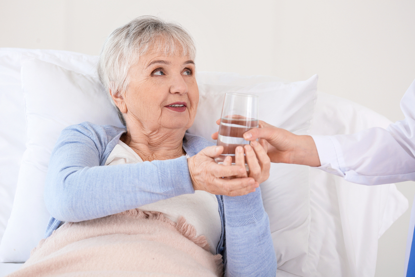 Female doctor giving senior woman suffering from Parkinson syndrome glass of water in clinic When Your Aging Parent Adapt To 24 Hour Care In Assisted Living Services In Keller, TX: Here's What Your Family Should Expect