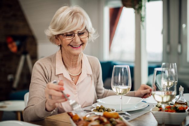 Happy mature woman enjoying in lunch at dining table. How Dining Program In Assisted Living In Lely, FL Is Designed To Meet Your Protein Needs