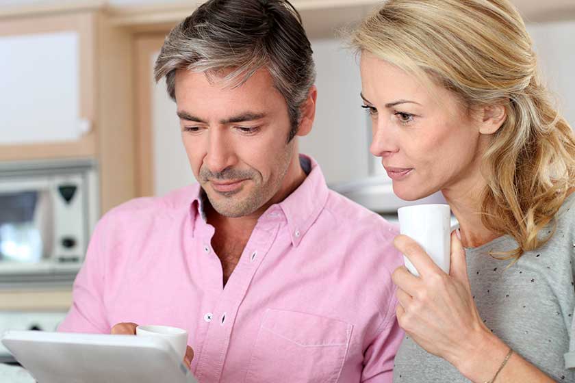 Middle aged couple using tablet in kitchen