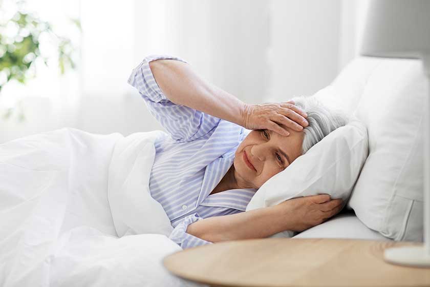 Senior woman with headache in bed at home Senior woman with headache in bed at home