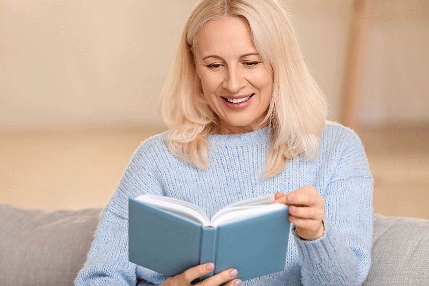 Beautiful mature woman reading book at home