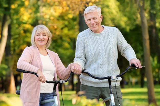 Cute elderly couple with bicycles in autumn park