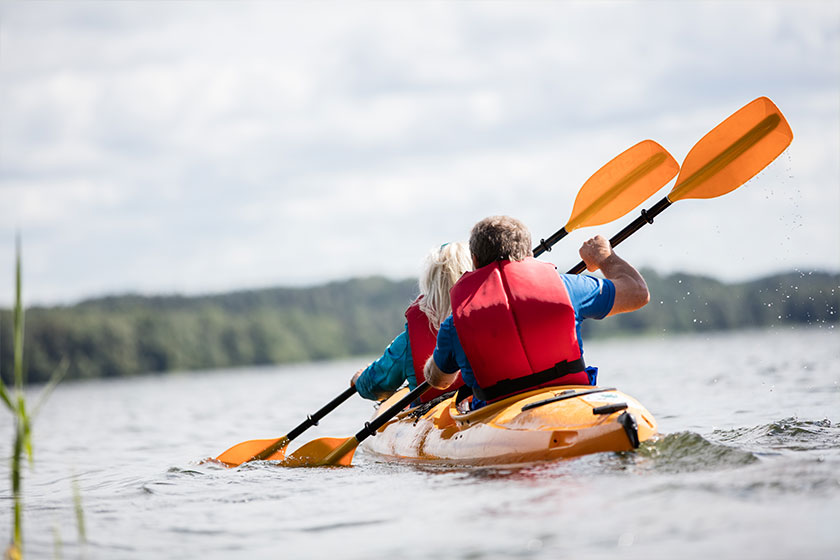Happy senior active couple kayaking on lake
