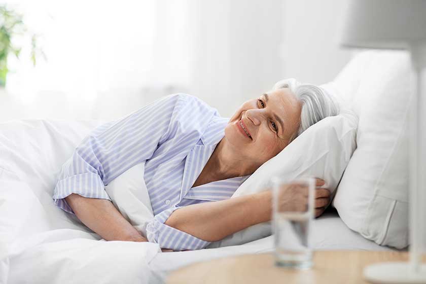 Happy senior woman lying in bed at home bedroom