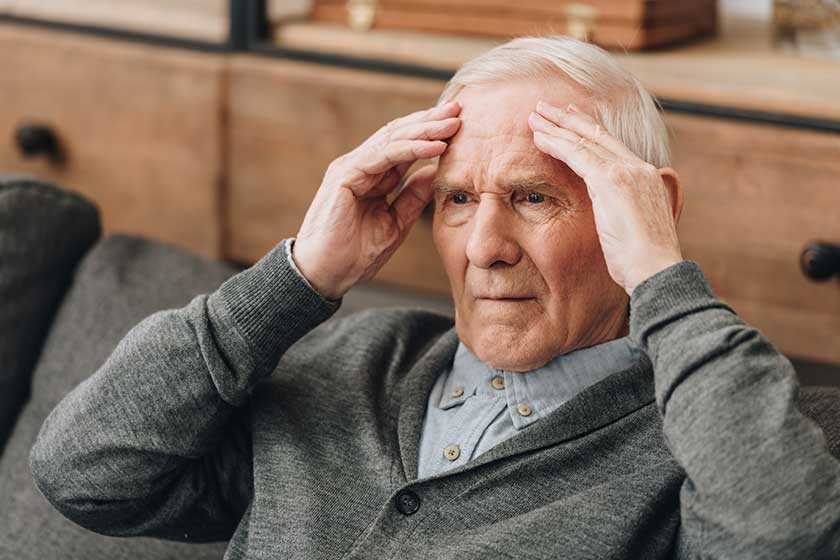 Retired man with grey hair having headache