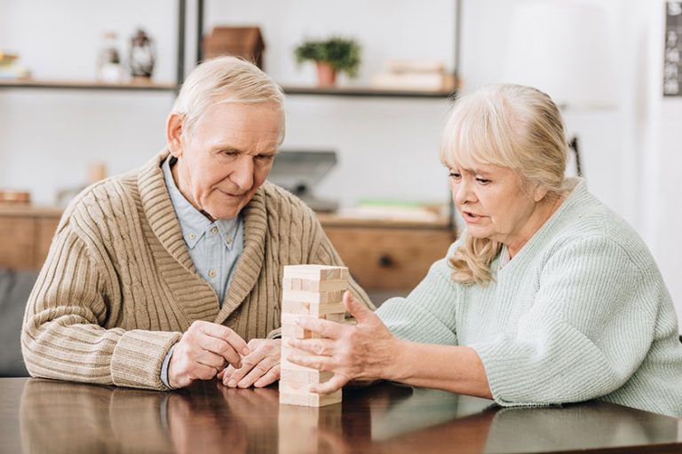 Senior couple playing jenga game at home Senior couple playing jenga game at home