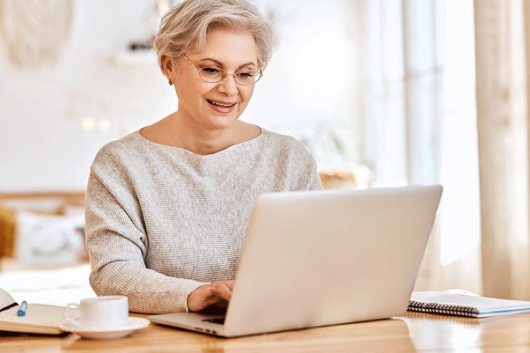 senior-woman-laptop-notebook-while-sitting-table-working-remote-project