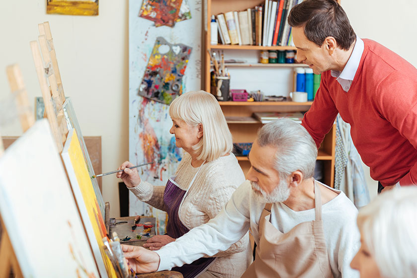 Handsome artist controlling his colleagues in painting class