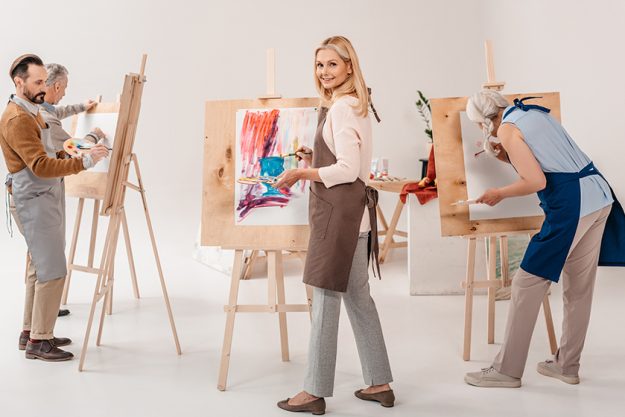 Male and female adult students in aprons