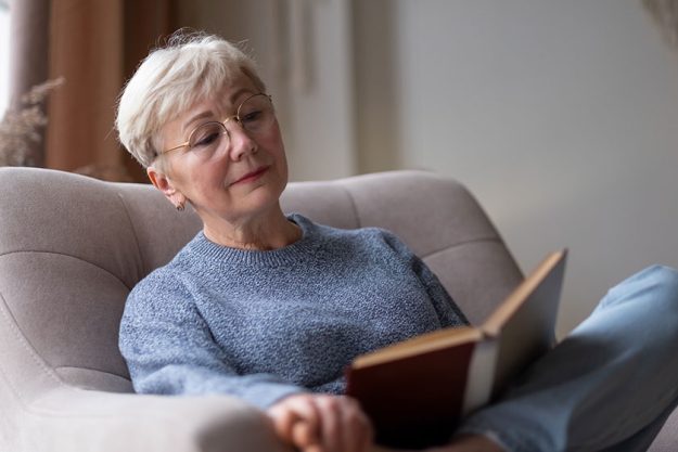Senior caucasian woman at home reading book