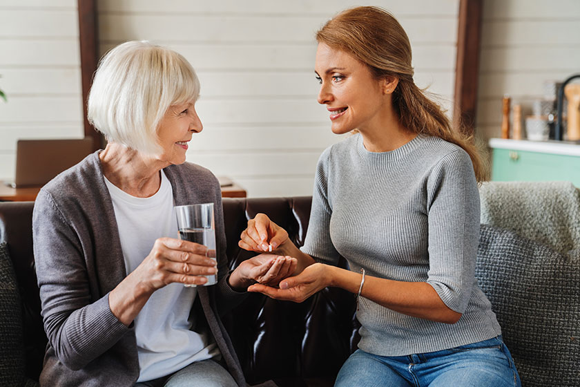 Senior woman taking pills from her daughter