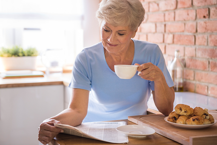 Woman drinking tea and reading paper Woman drinking tea and reading paper