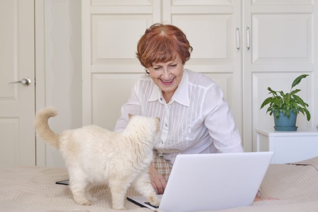 Senior woman using a laptop at home. Happy retired person shopping online.