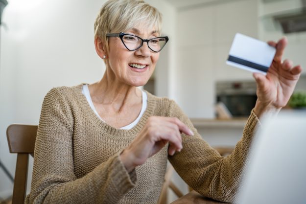 Senior woman caucasian female hold credit card online shopping a