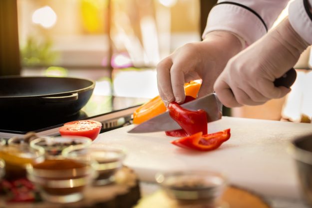 Hand with knife cutting pepper. Hand with knife cutting pepper.