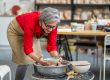 Woman potter taking finished plate from pottery wheel, making earthenware.