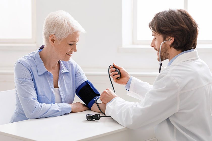 Doctor measuring blood pressure of senior woman at clinic