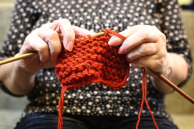 Elderly woman is engaged in knitting warm sweaters for her grand