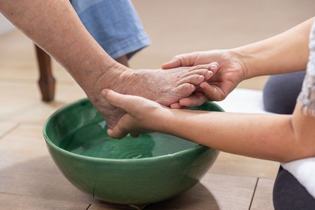 Female caregiver wipes the elderly woman feet by towel Female caregiver wipes the elderly woman feet by towel