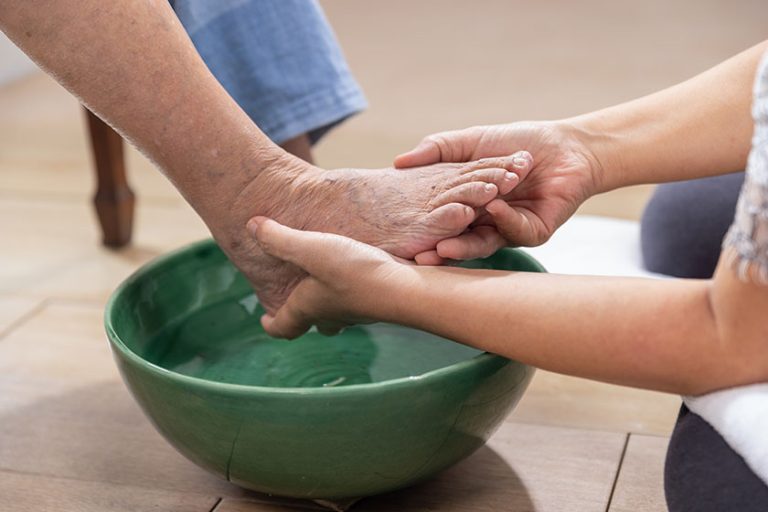Female caregiver wipes the elderly woman feet by towel Female caregiver wipes the elderly woman feet by towel