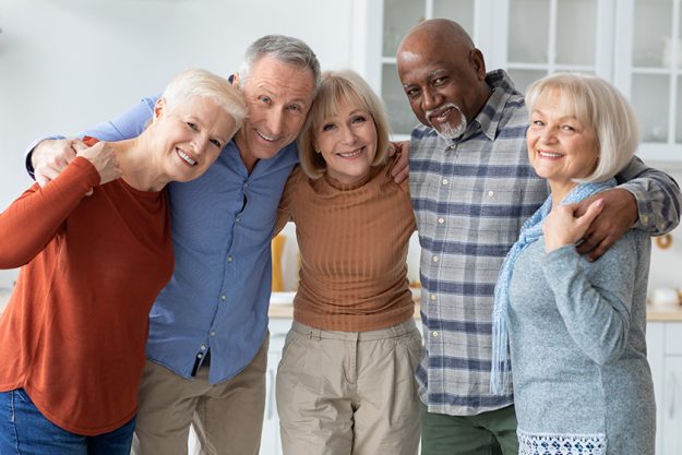 Group photo of happy elderly people hugging, smiling at camera