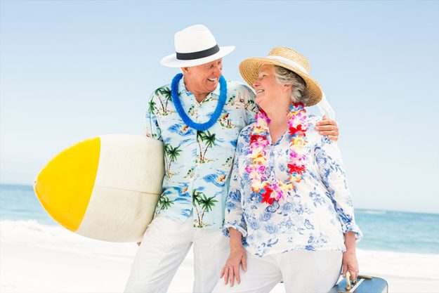 Senior couple holding surfboard