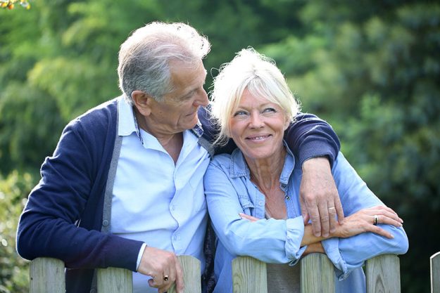 Senior couple standing by fence