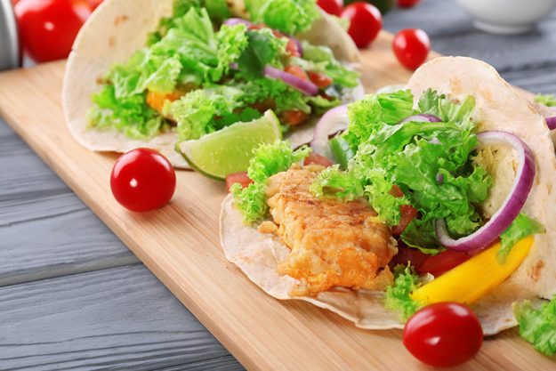 Wooden board with delicious tacos