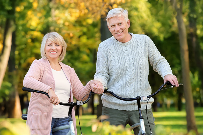 Cute elderly couple with bicycles in autumn park
