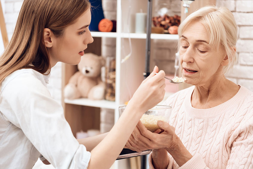 Girl nursing elderly woman in wheelchair