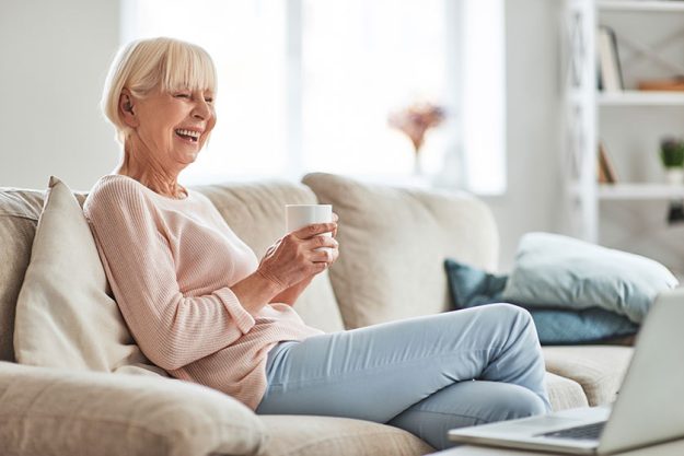 Laughing senior caucasian woman sitting on sofa