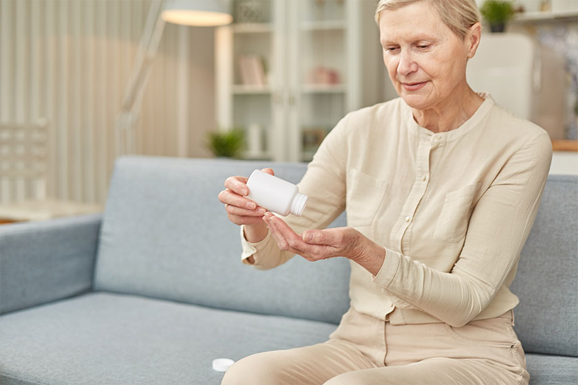 Senior woman sit on couch having daily vitamins
