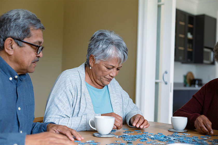 Two diverse female and male friends sitting at table and doing puzzles Two diverse female and male friends sitting at table and doing puzzles
