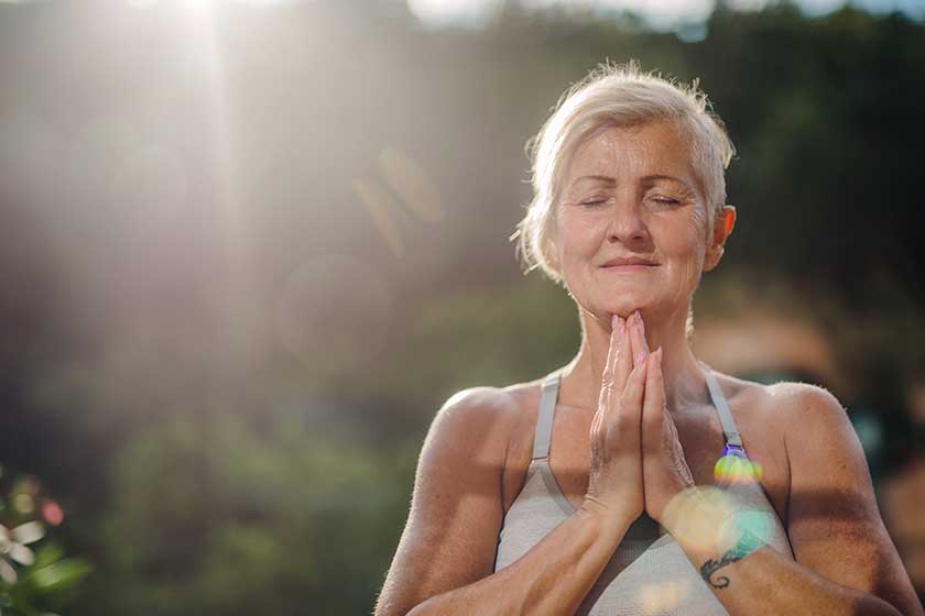 A senior woman standing outdoors on a terrace in summer, doing yoga A senior woman standing outdoors on a terrace in summer, doing yoga