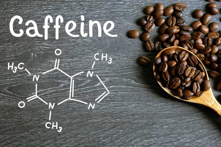 Coffee beans with wooden spoon and chemical structure of caffeine on a wooden table