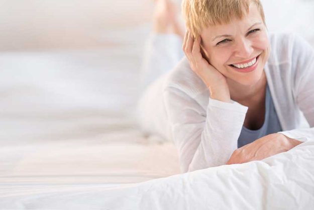 Happy Mature Woman Lying In Bed