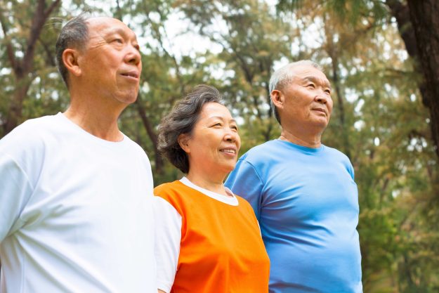 Happy senior sibling standing a row in park Happy senior sibling standing a row in park