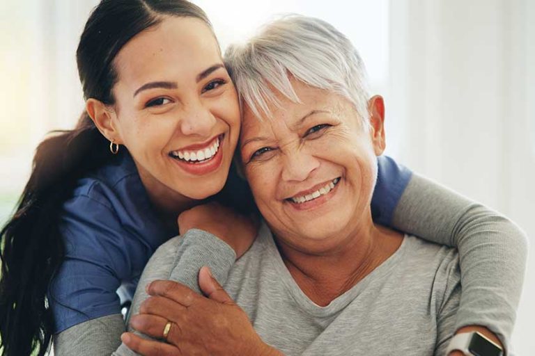 Happy woman, nurse and hug senior patient in elderly care, support or trust at old age home. Portrait of mature female person, doctor or medical caregiver hugging with smile for embrace at house
