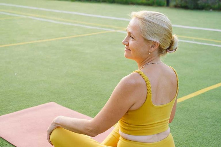 Mature caucasian woman meditating outdoors on sunset on sport ground. Senior woman practice mindfulness Mature caucasian woman meditating outdoors on sunset on sport ground. Senior woman practice mindfulness