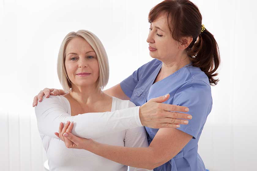 Physiotherapist working with middle aged patient in clinic Physiotherapist working with middle aged patient in clinic