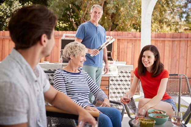 Senior couple and adult children barbecuing outside house Senior couple and adult children barbecuing outside house