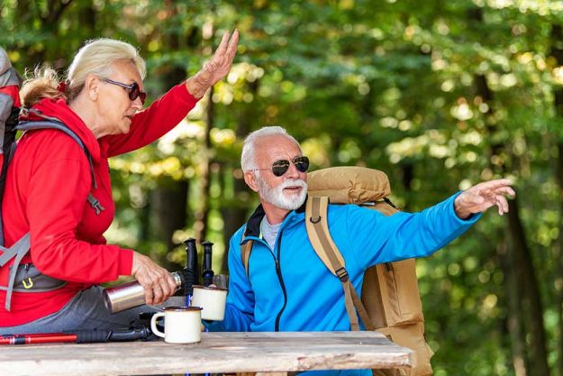 Senior couple sitting and drink coffee while hiking in the forest. Senior couple sitting and drink coffee while hiking in the forest.