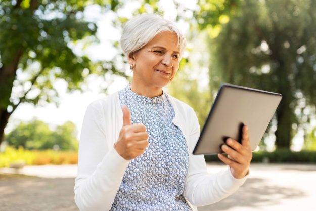 Senior woman with tablet pc showing thumbs up