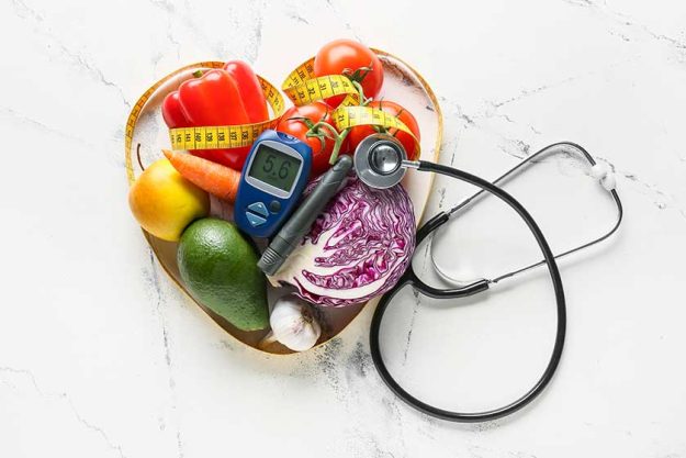 Vegetables, stethoscope, measuring tape, lancet pen and glucometer white background Vegetables, stethoscope, measuring tape, lancet pen and glucometer white background